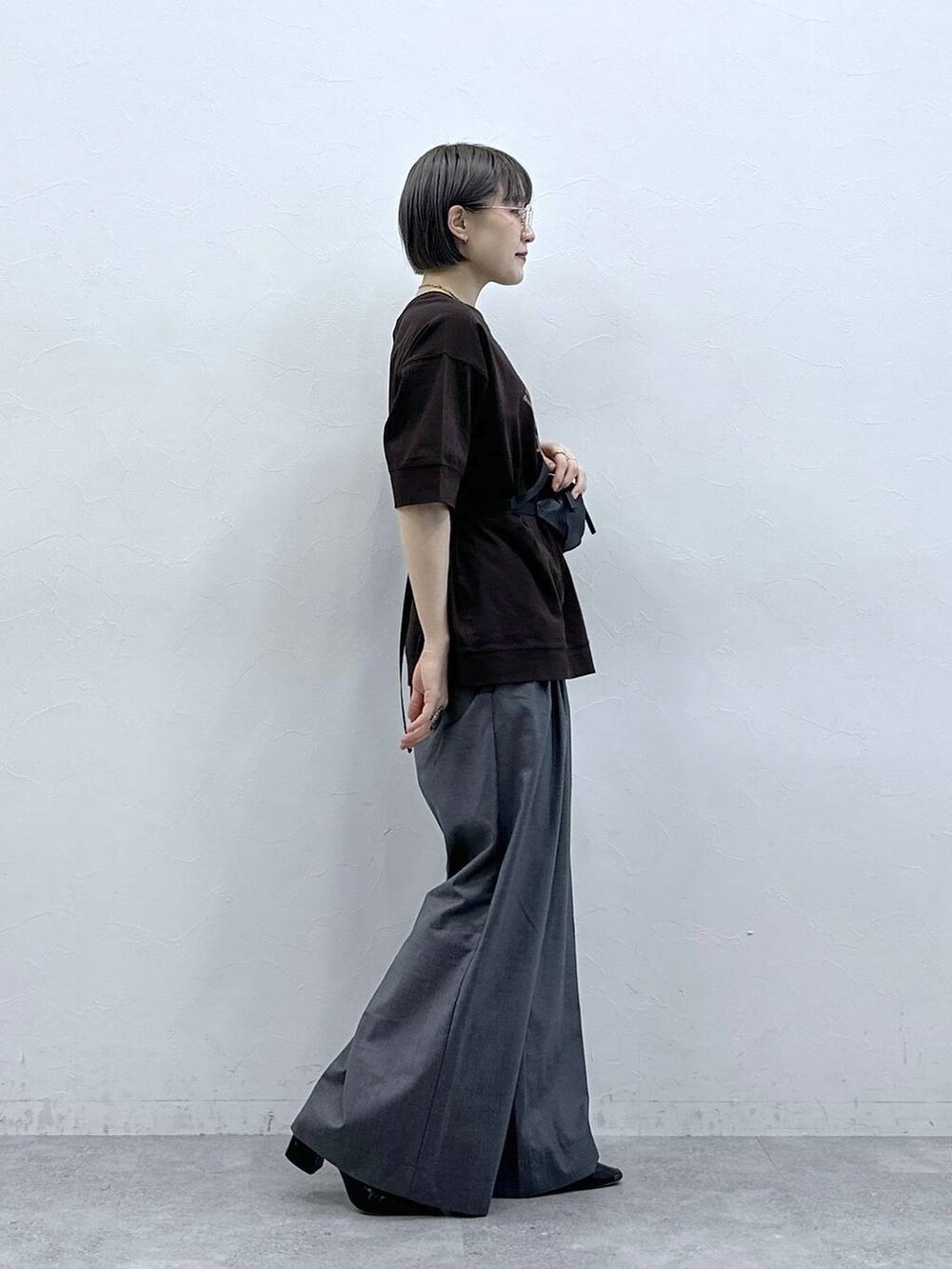 ブラウン系のTシャツ/カットソー、ブラック系のボディバッグ/ウエストポーチ、グレー系のスラックスを着用したレディースの春コーディネートの5枚目の写真