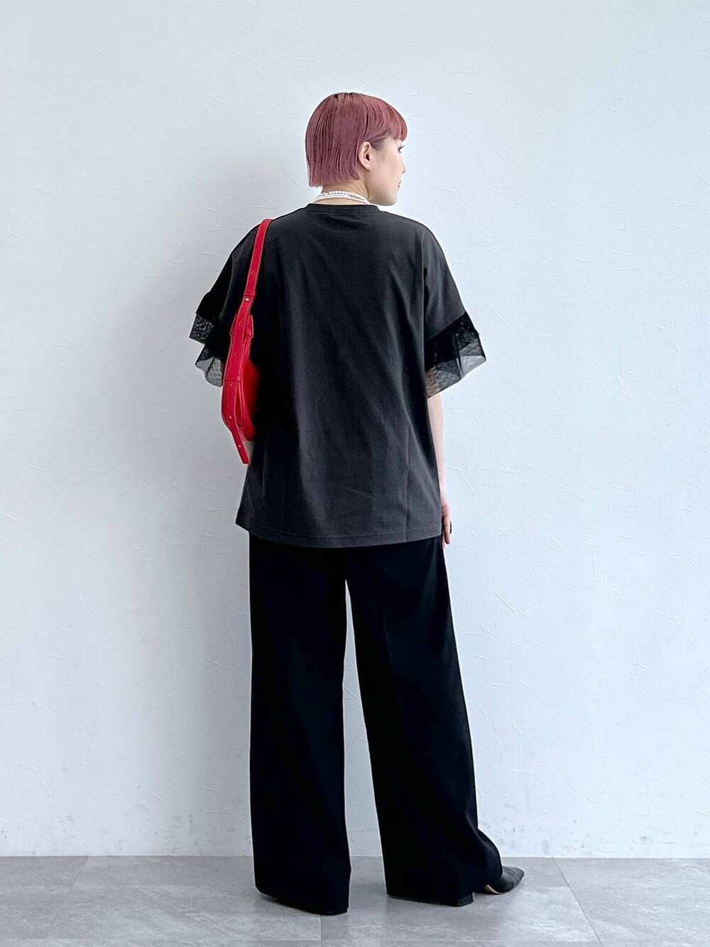 レッド系のショルダーバッグ、ブラック系のスラックス、ブラック系のTシャツ/カットソーを着用したレディースの春コーディネートの5枚目の写真