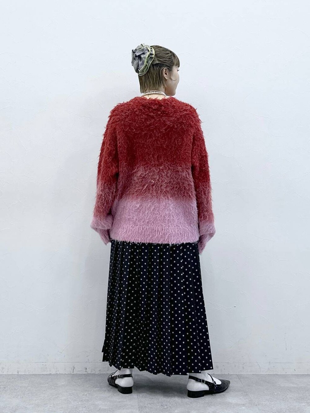 レッド系のニット/セーター、ブラック系のパンプス、ブラック系のスカートを着用したレディースの冬コーディネートの4枚目の写真