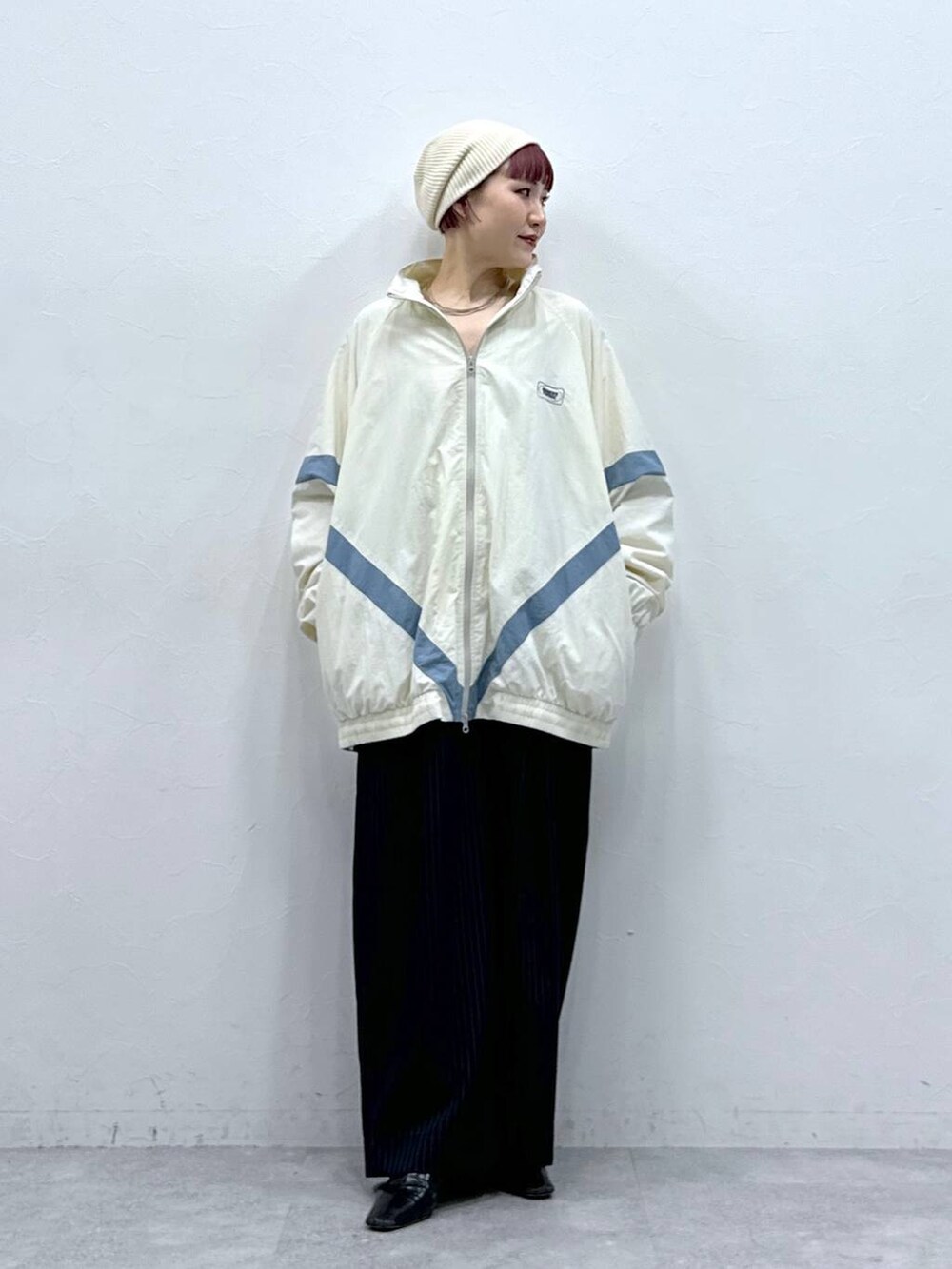 ホワイト系のブルゾン、ブラック系のスラックスを着用したレディースの春コーディネートの4枚目の写真