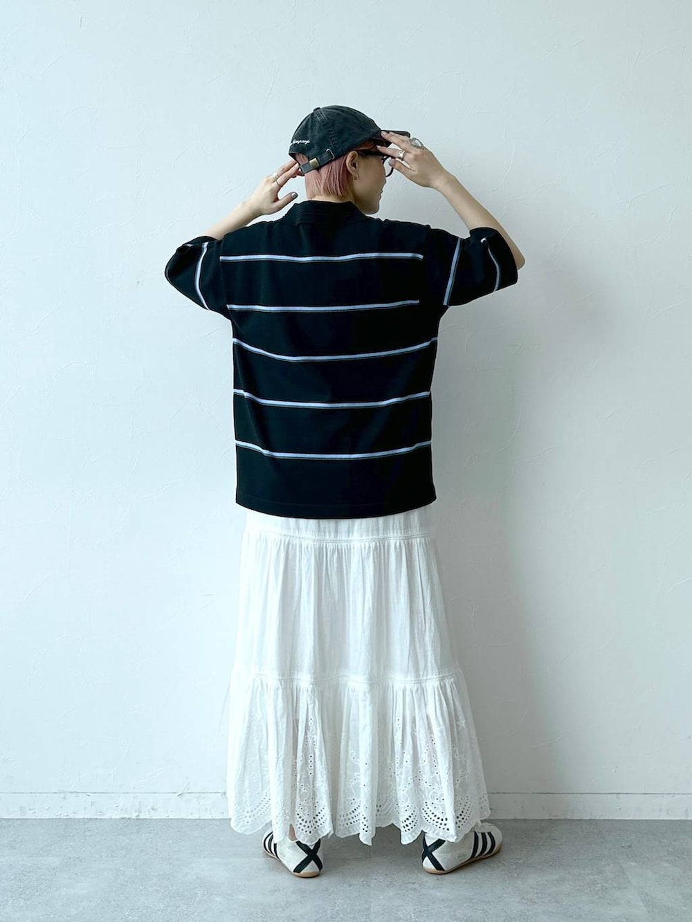 ホワイト系のスニーカー、ブラック系のポロシャツ、ホワイト系のスカートを着用したレディースの春コーディネートの5枚目の写真