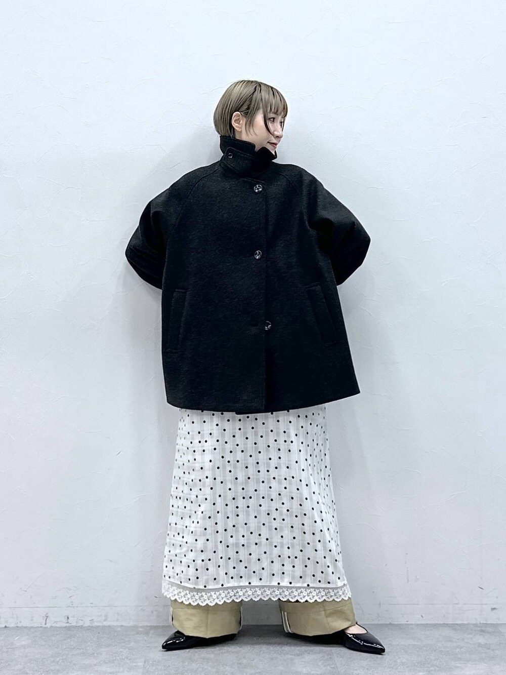 ブラック系のパンプス、ブラック系のステンカラーコート、ベージュ系のチノパンツを着用したレディースの冬コーディネートの3枚目の写真