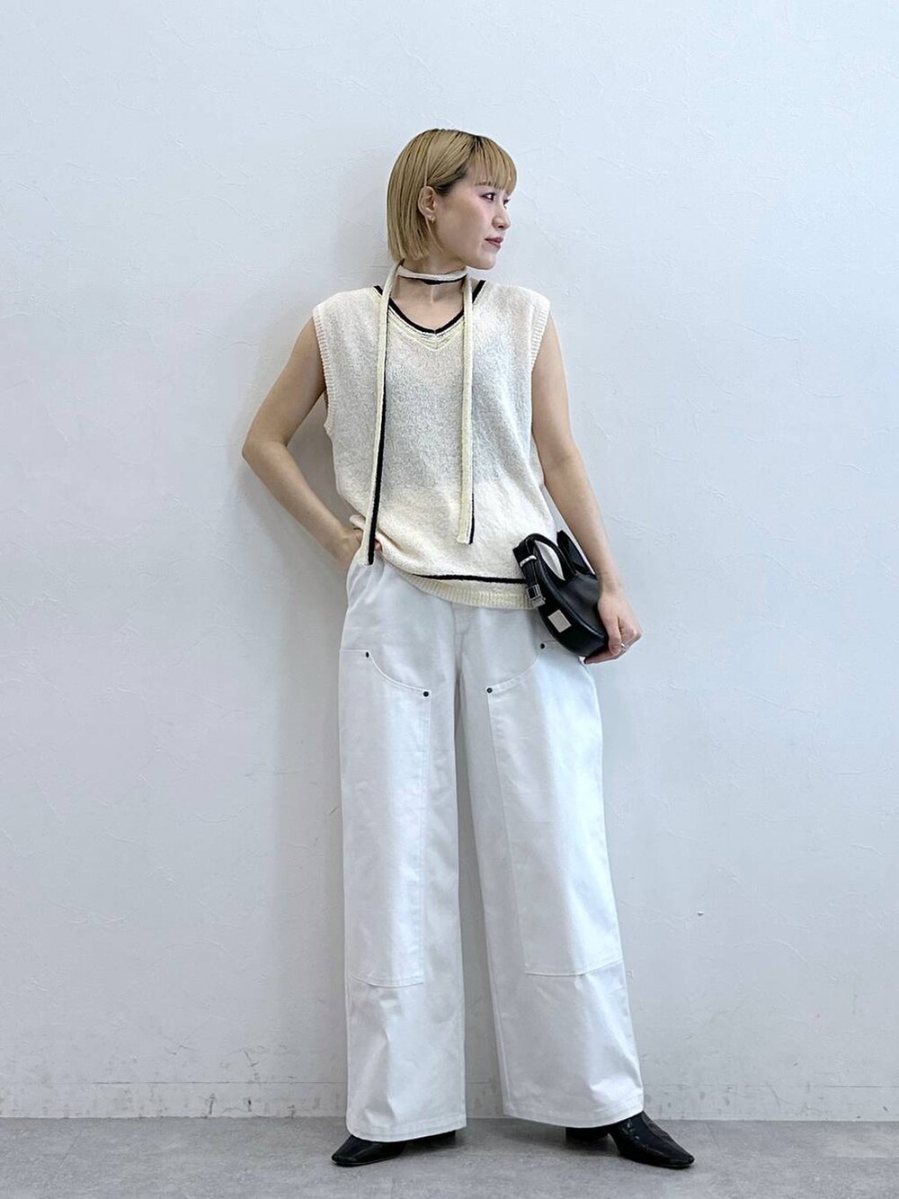 ホワイト系のニット/セーター、ホワイト系のチノパンツを着用したレディースの夏コーディネートの4枚目の写真