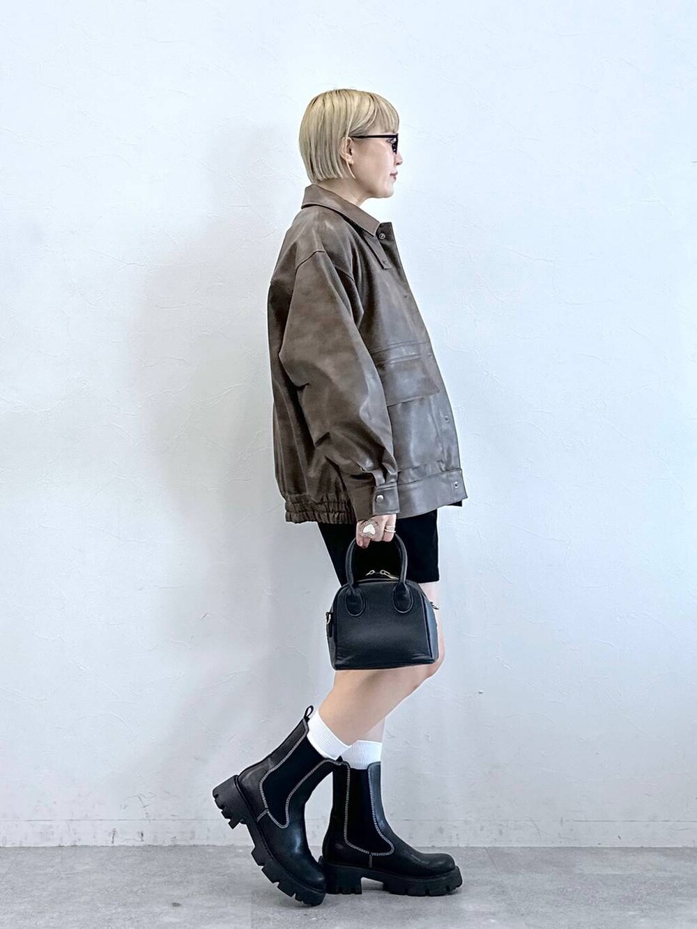 ブラック系のチノパンツ、ブラック系のブーツ、ブラウン系のブルゾンを着用したレディースの冬コーディネートの2枚目の写真