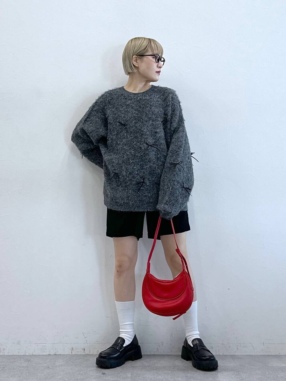 ブラック系のチノパンツ、レッド系のショルダーバッグ、グレー系のニット/セーターを着用したレディースの冬コーディネートの6枚目の写真