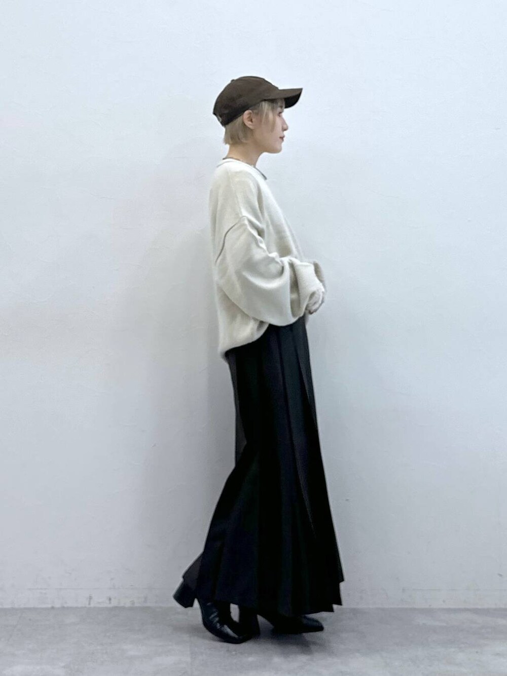 ホワイト系のニット/セーター、ブラウン系のスカート、ホワイト系のTシャツ/カットソーを着用したレディースの秋コーディネートの6枚目の写真