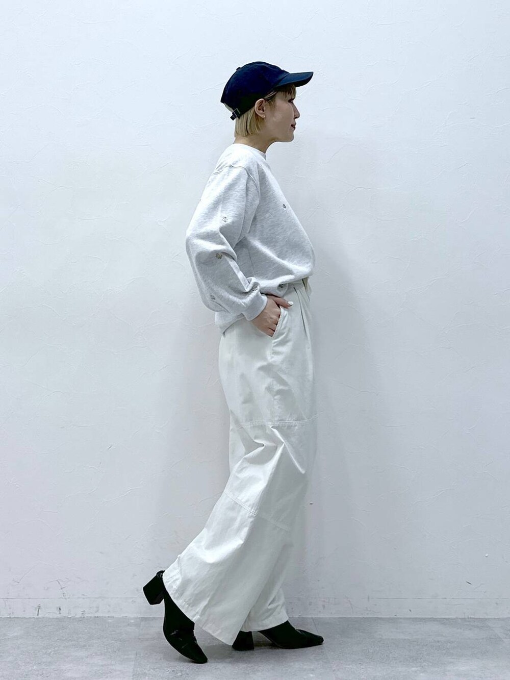 ホワイト系のカーゴパンツ、ホワイト系のスウェット、ブラック系のキャップを着用したレディースの冬コーディネートの4枚目の写真