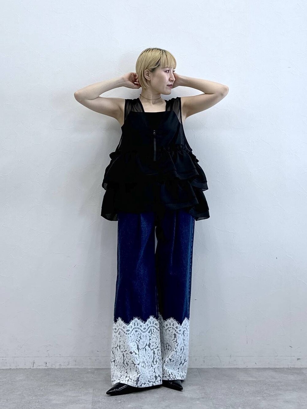 ブルー系のデニムパンツ、ブラック系のベスト、ブラック系のキャミソールを着用したレディースの春コーディネートの3枚目の写真