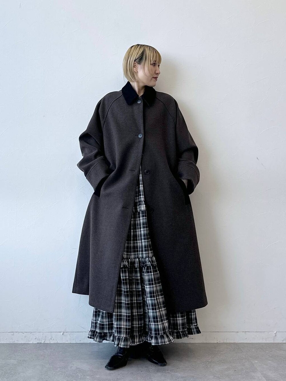 ブラウン系のステンカラーコート、ブラック系のスカートを着用したレディースの冬コーディネートの4枚目の写真