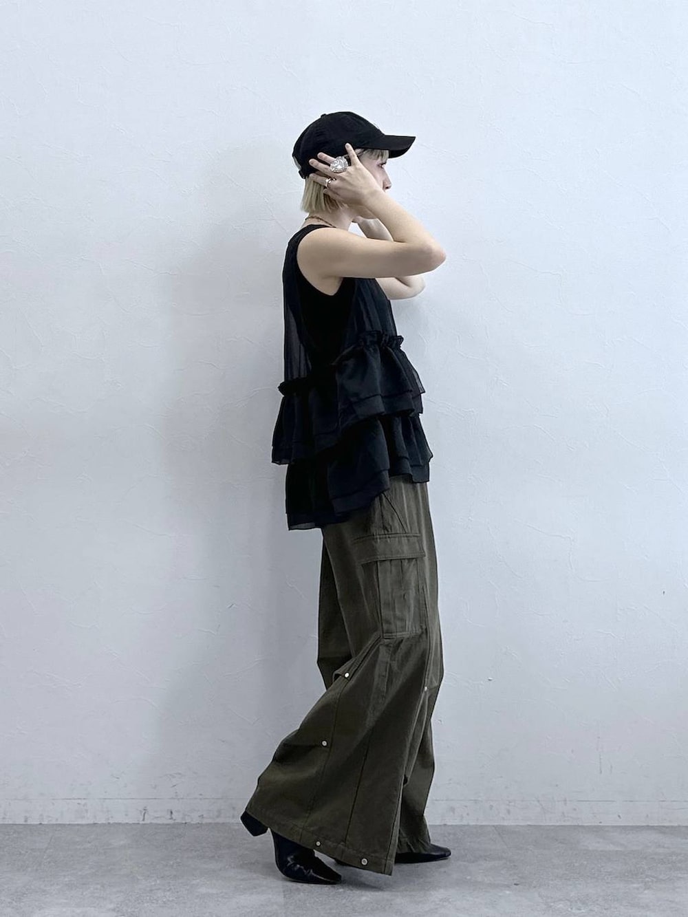 グリーン系のカーゴパンツ、ブラック系のタンクトップ、ブラック系のベストを着用したレディースの夏コーディネートの4枚目の写真