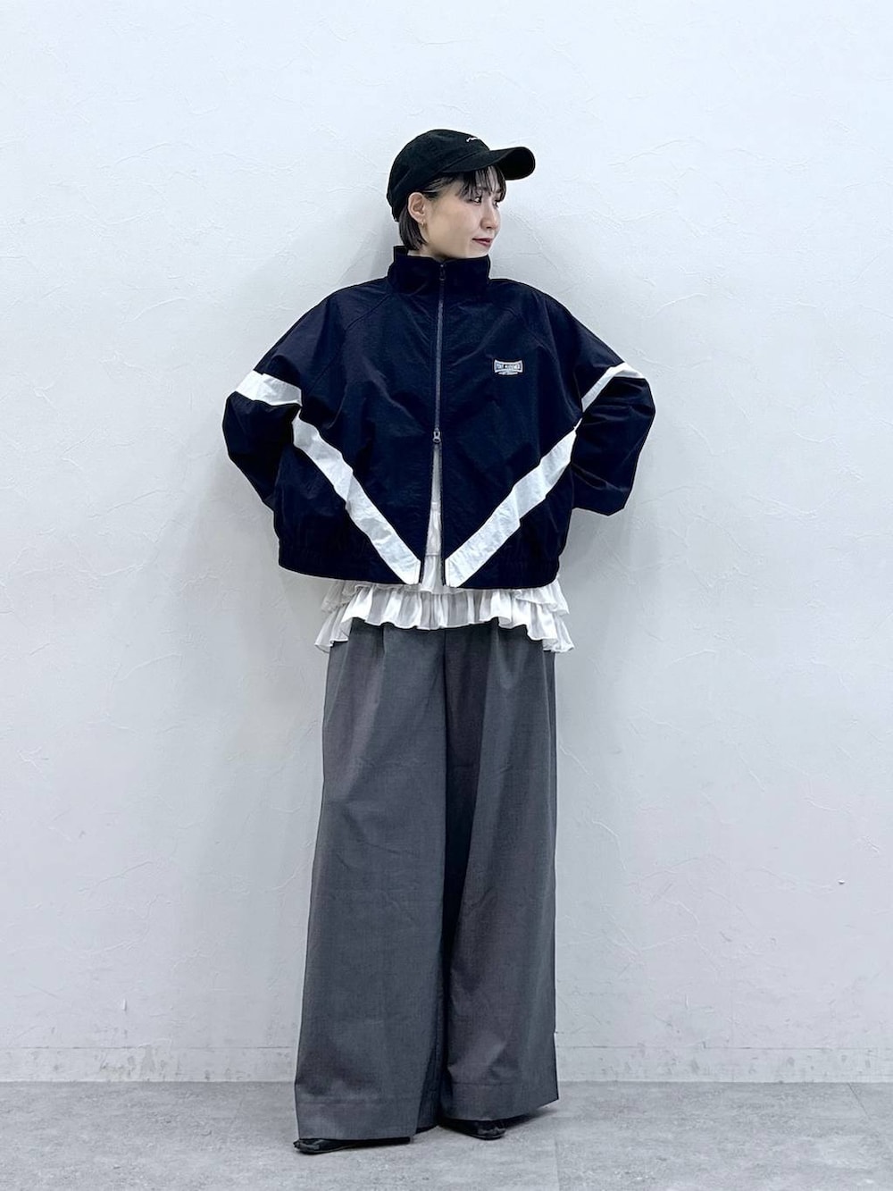 ホワイト系のキャミソール、ブルー系のブルゾン、グレー系のスラックスを着用したレディースの春コーディネートの4枚目の写真