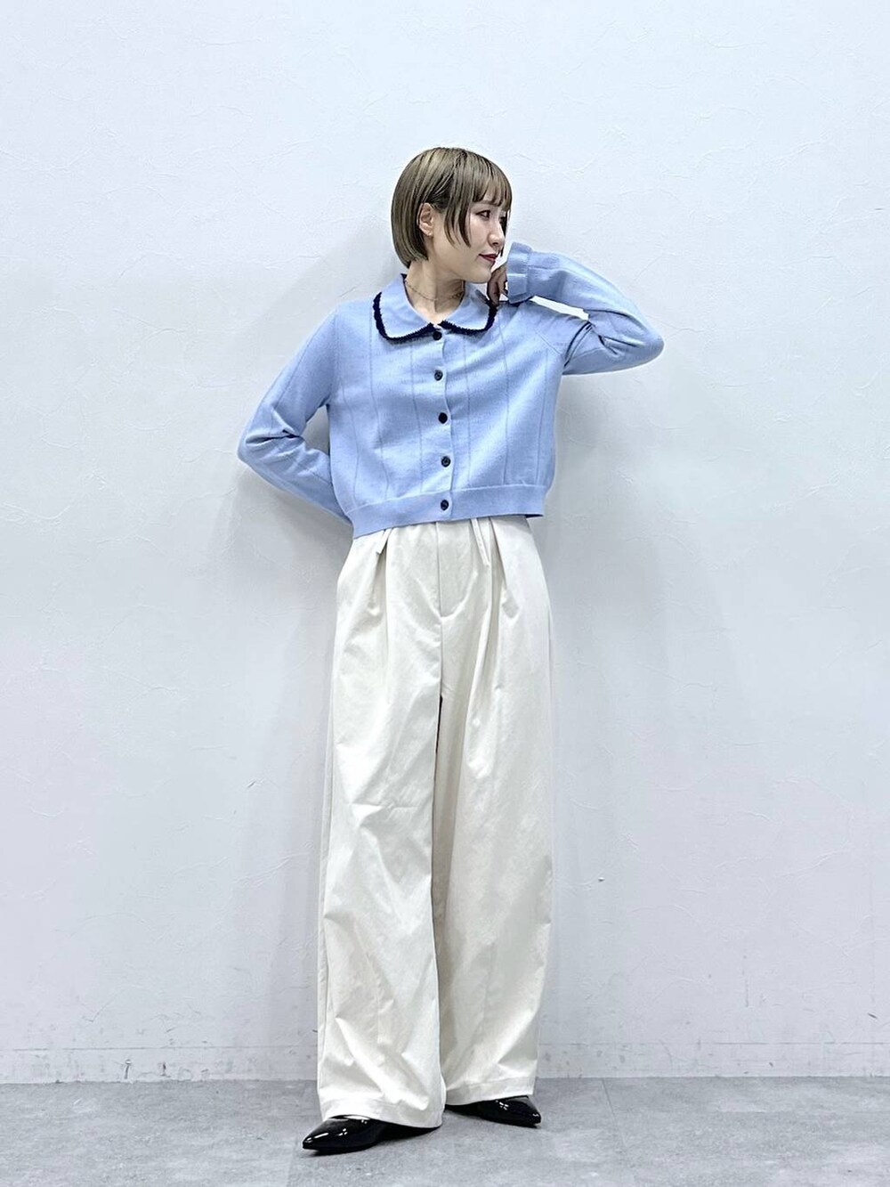 ホワイト系のチノパンツ、ブルー系のカーディガン/ボレロ、ブラック系のパンプスを着用したレディースの冬コーディネートの3枚目の写真