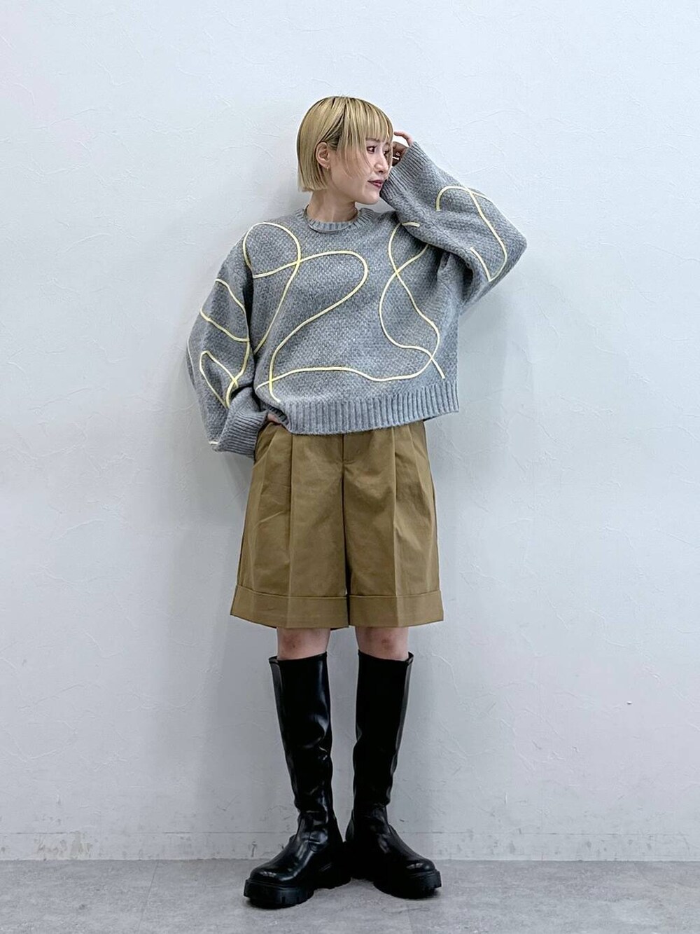 ブラック系のブーツ、ブラウン系のチノパンツ、グレー系のニット/セーターを着用したレディースの秋コーディネートの2枚目の写真