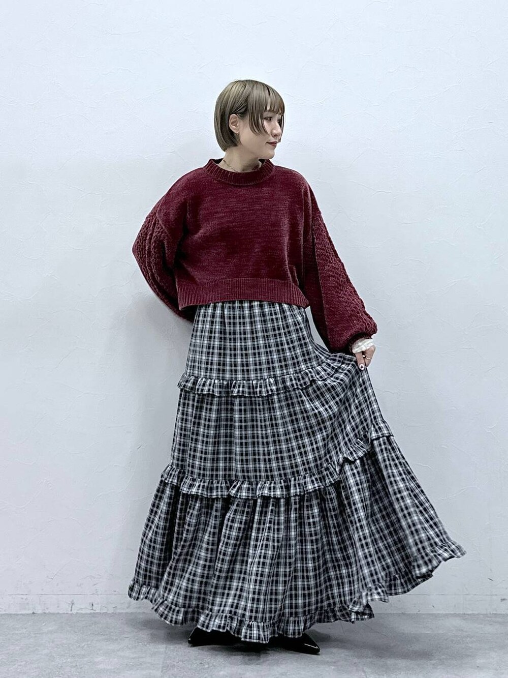 レッド系のニット/セーター、ブラック系のスカート、ブラック系のパンプスを着用したレディースの冬コーディネートの3枚目の写真