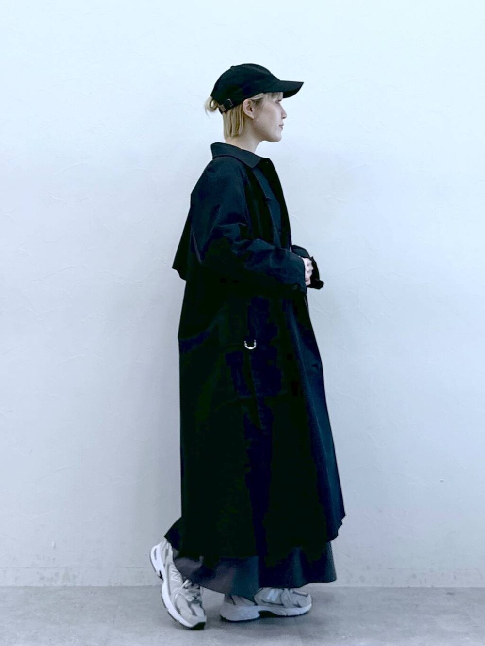 ブラック系のトレンチコート、グレー系のワンピース、ブラック系のキャップを着用したレディースの冬コーディネートの3枚目の写真