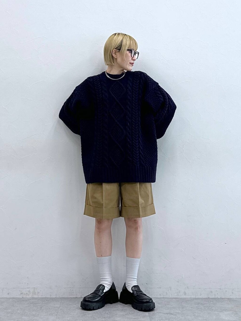 ブラック系のローファー、ブラウン系のチノパンツ、ブルー系のニット/セーターを着用したレディースの秋コーディネートの2枚目の写真