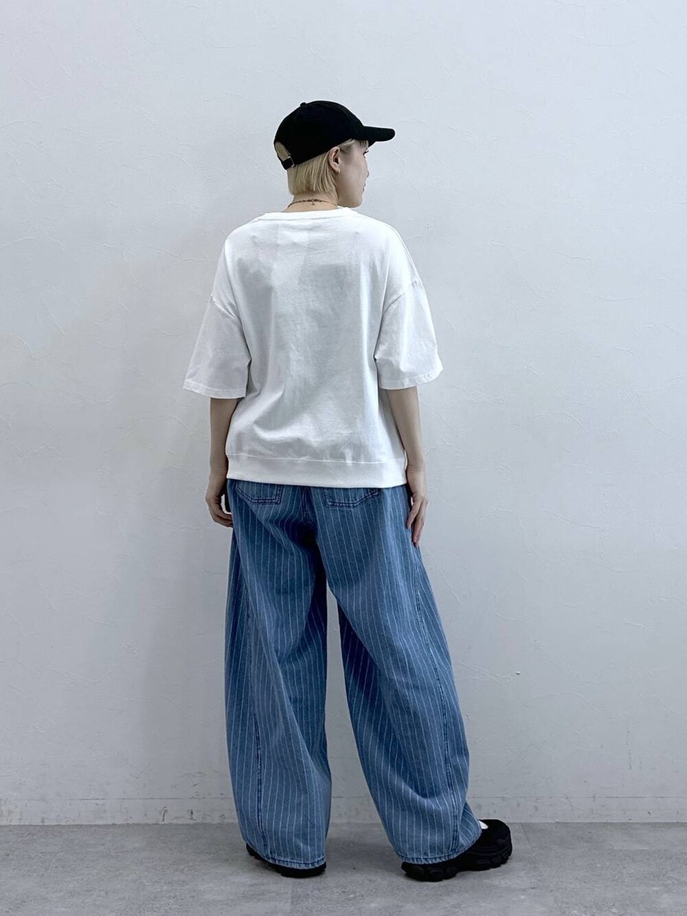 ホワイト系のTシャツ/カットソー、ブラック系のサンダル、ブルー系のデニムパンツを着用したレディースの春コーディネートの5枚目の写真