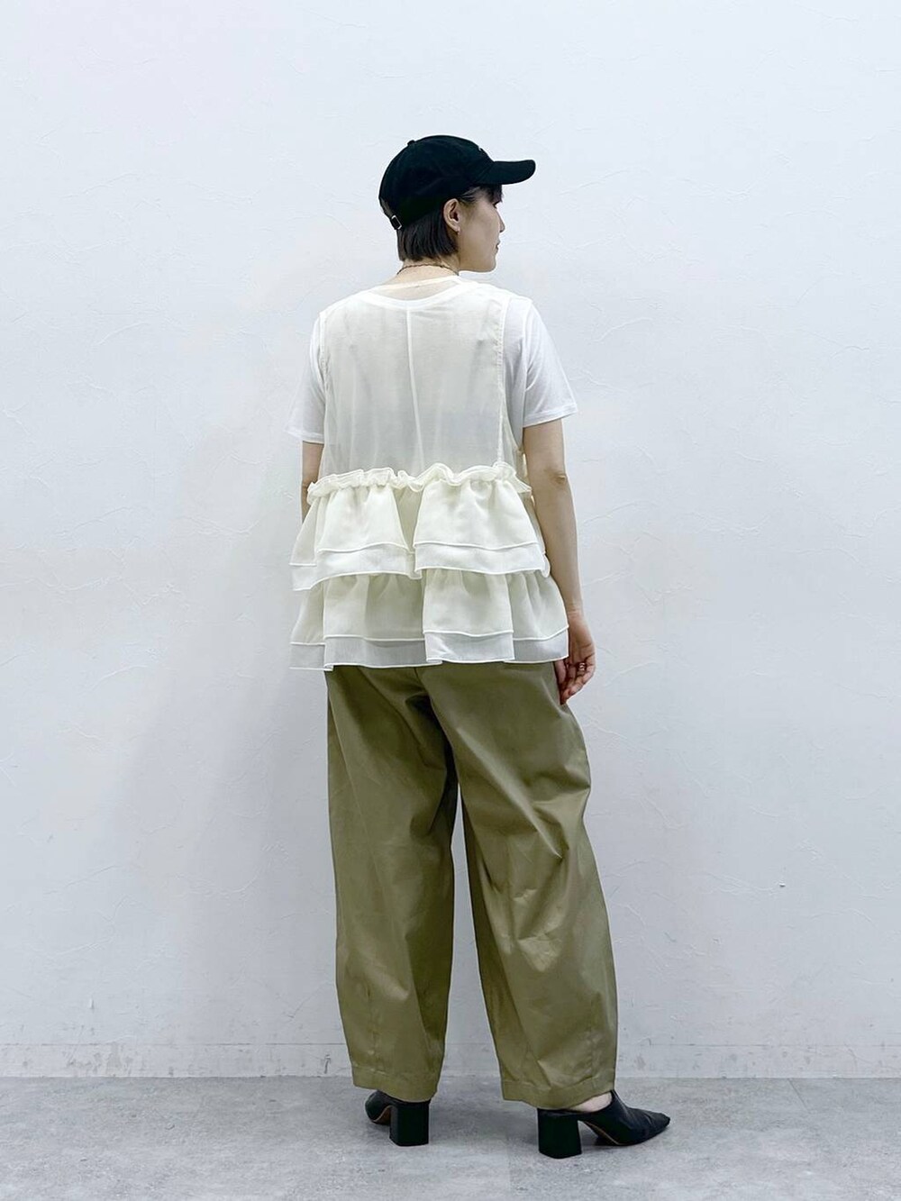 ベージュ系のチノパンツ、ホワイト系のTシャツ/カットソー、ホワイト系のベストを着用したレディースの春コーディネートの5枚目の写真