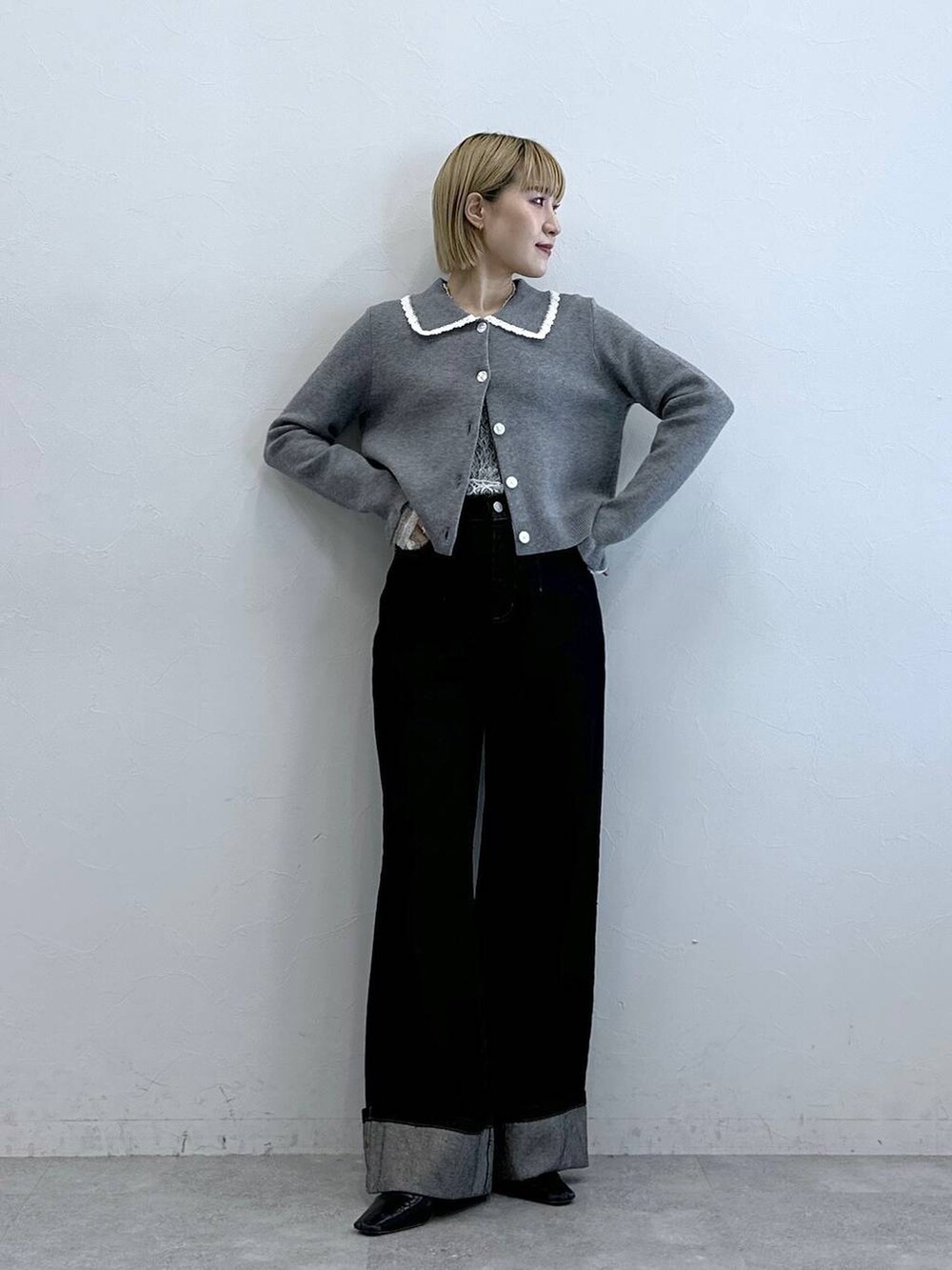 ブラック系のデニムパンツ、ホワイト系のTシャツ/カットソー、グレー系のニット/セーターを着用したレディースの夏コーディネートの3枚目の写真