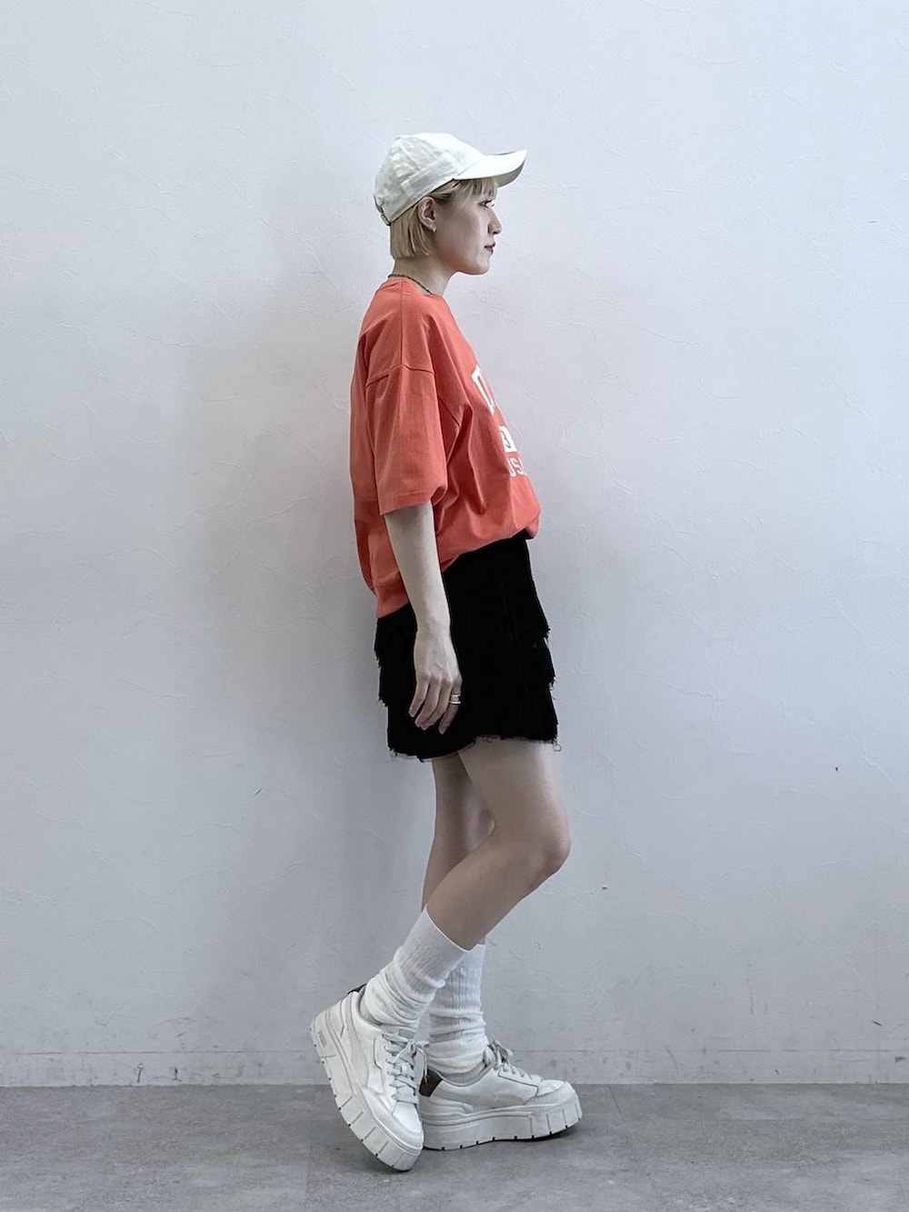 レッド系のTシャツ/カットソー、ブラック系のスカート、ホワイト系のキャップを着用したレディースの春コーディネートの4枚目の写真