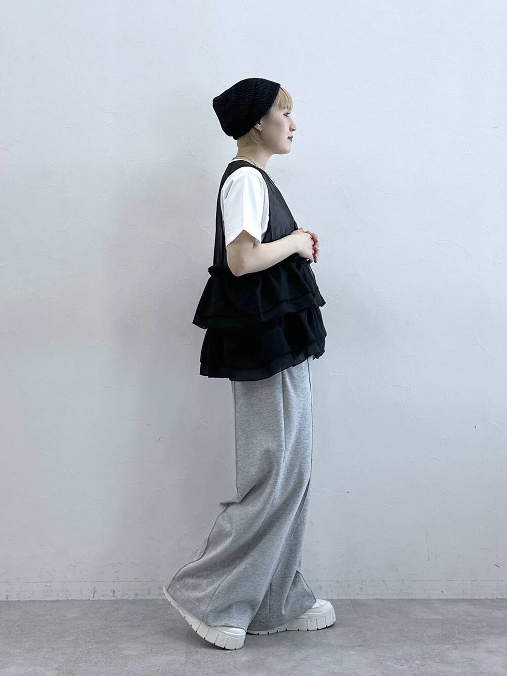 グレー系のスウェットパンツ、ホワイト系のTシャツ/カットソー、ブラック系のベストを着用したレディースの春コーディネートの4枚目の写真