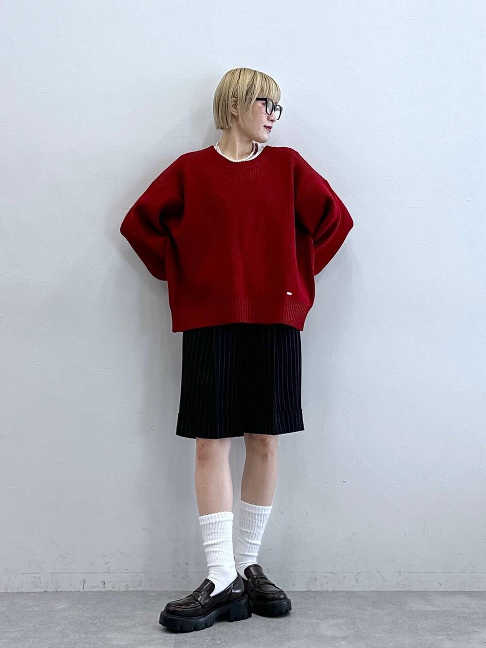 ブラック系のローファー、ブラック系のスラックス、レッド系のニット/セーターを着用したレディースの秋コーディネートの2枚目の写真