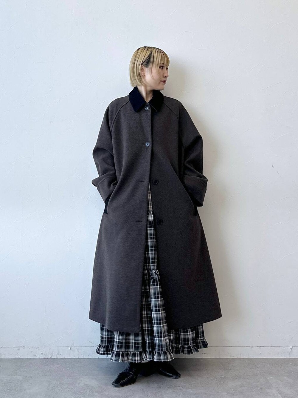 ブラウン系のステンカラーコート、ブラック系のスカートを着用したレディースの冬コーディネートの3枚目の写真