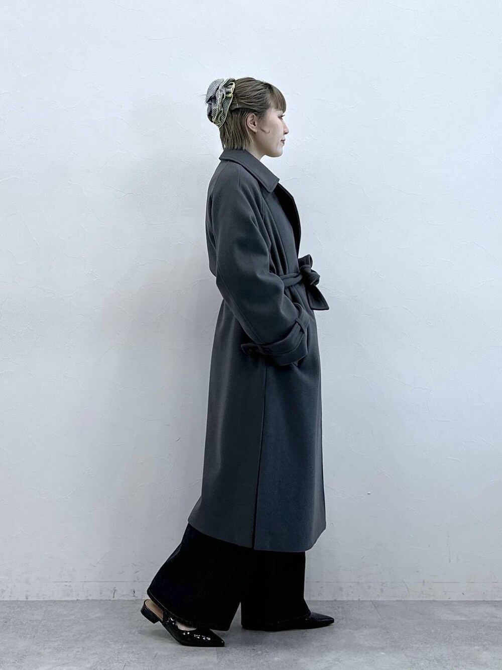 グレー系のステンカラーコート、ブラック系のニット/セーター、ブラック系のパンプスを着用したレディースの冬コーディネートの5枚目の写真