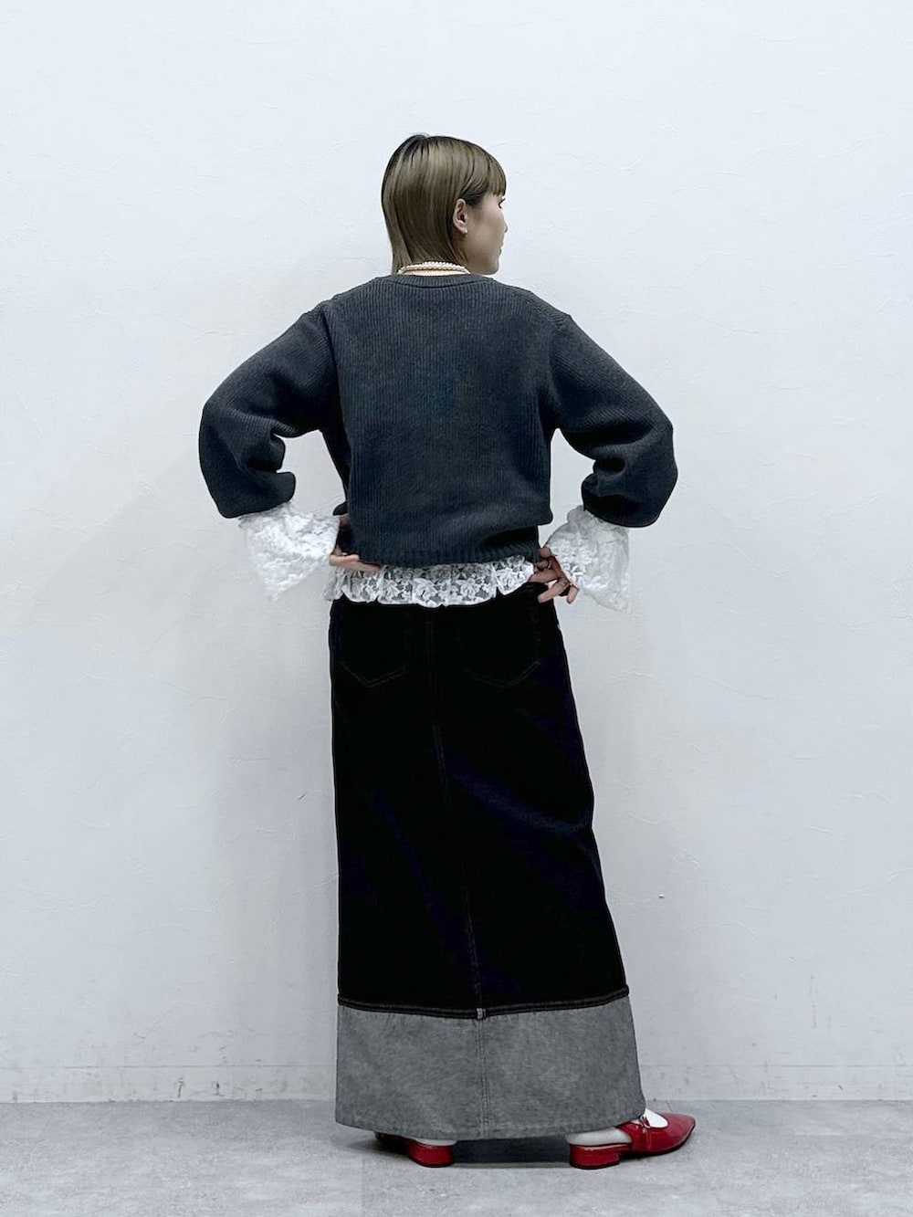 レッド系のパンプス、グレー系のニット/セーター、ブラック系のデニムスカートを着用したレディースの冬コーディネートの5枚目の写真