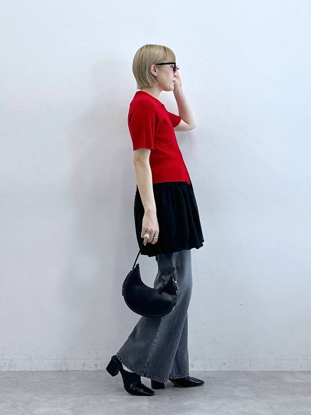 レッド系のニット/セーター、グレー系のデニムパンツ、ブラック系のスカートを着用したレディースの夏コーディネートの6枚目の写真