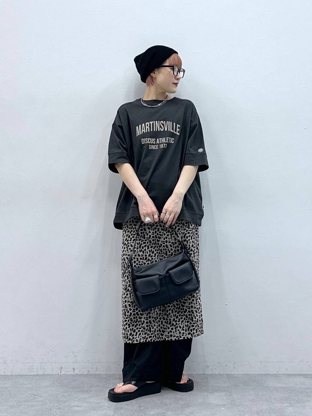 ブラック系のスラックス、グレー系のTシャツ/カットソー、ベージュ系のスカートを着用したレディースの春コーディネートの2枚目の写真