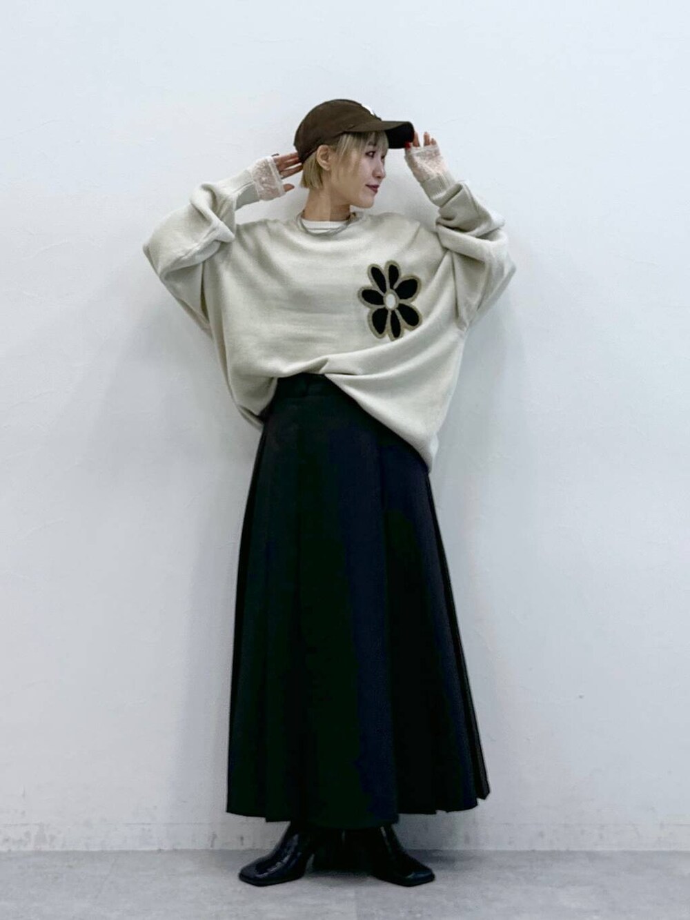 ホワイト系のニット/セーター、ブラウン系のスカート、ホワイト系のTシャツ/カットソーを着用したレディースの秋コーディネートの4枚目の写真