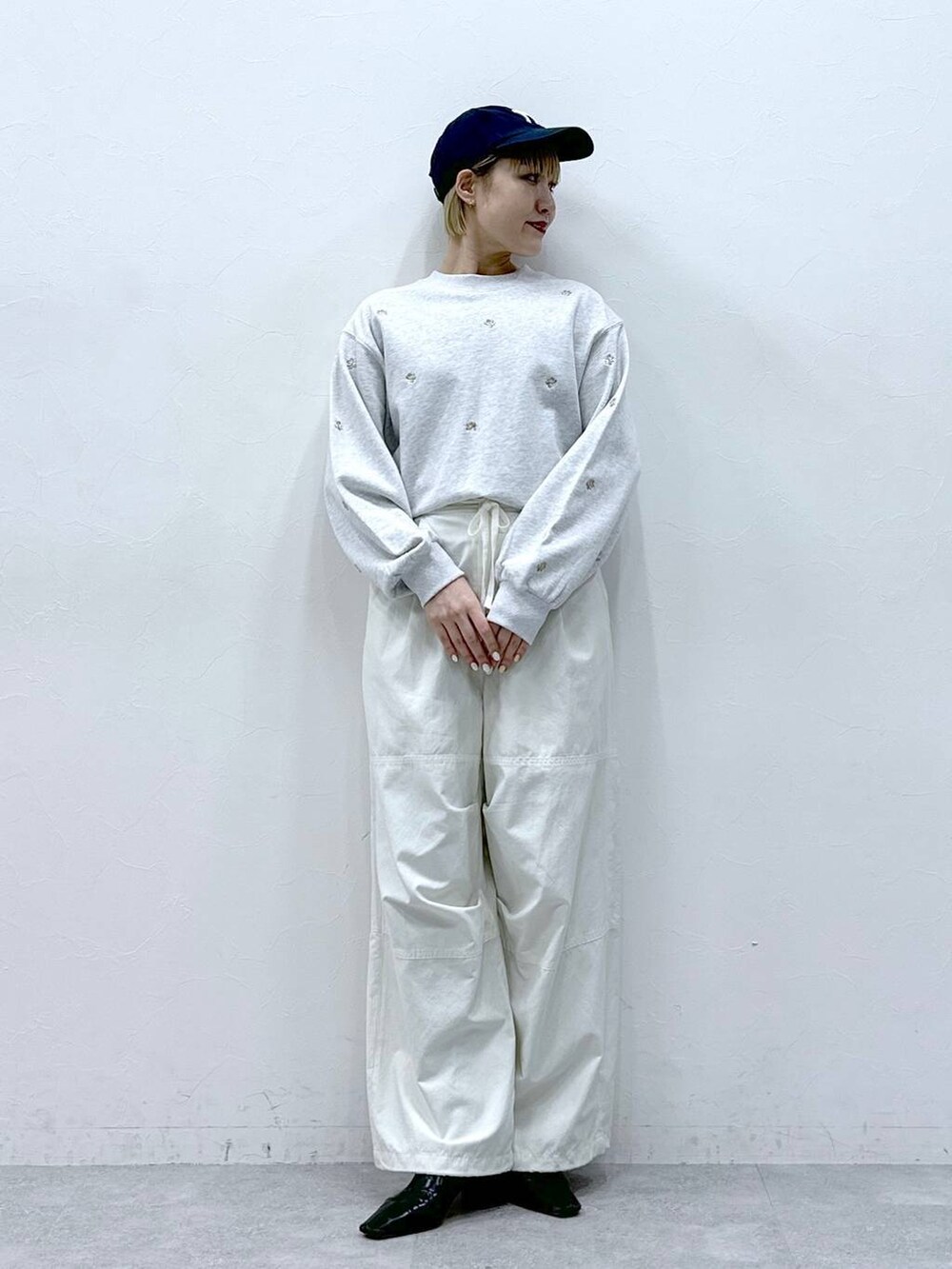 ホワイト系のカーゴパンツ、ホワイト系のスウェット、ブラック系のキャップを着用したレディースの冬コーディネートの2枚目の写真