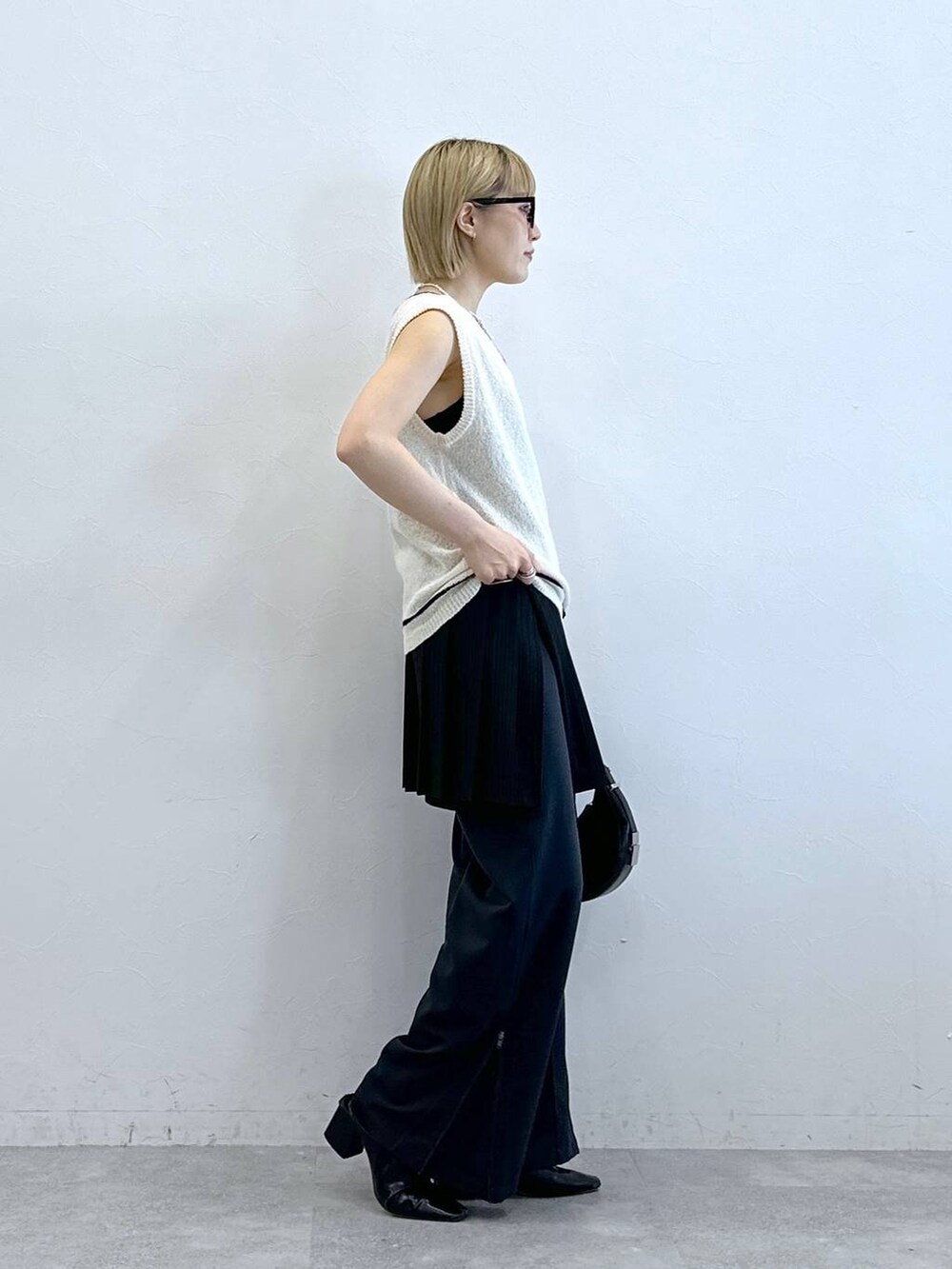 ホワイト系のニット/セーター、その他のスラックス、ブラック系のスカートを着用したレディースの夏コーディネートの6枚目の写真