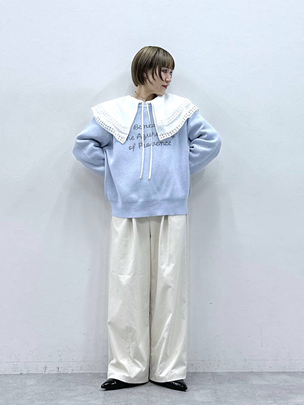 ホワイト系のチノパンツ、ホワイト系のシャツ/ブラウス、ブルー系のニット/セーターを着用したレディースの冬コーディネートの4枚目の写真