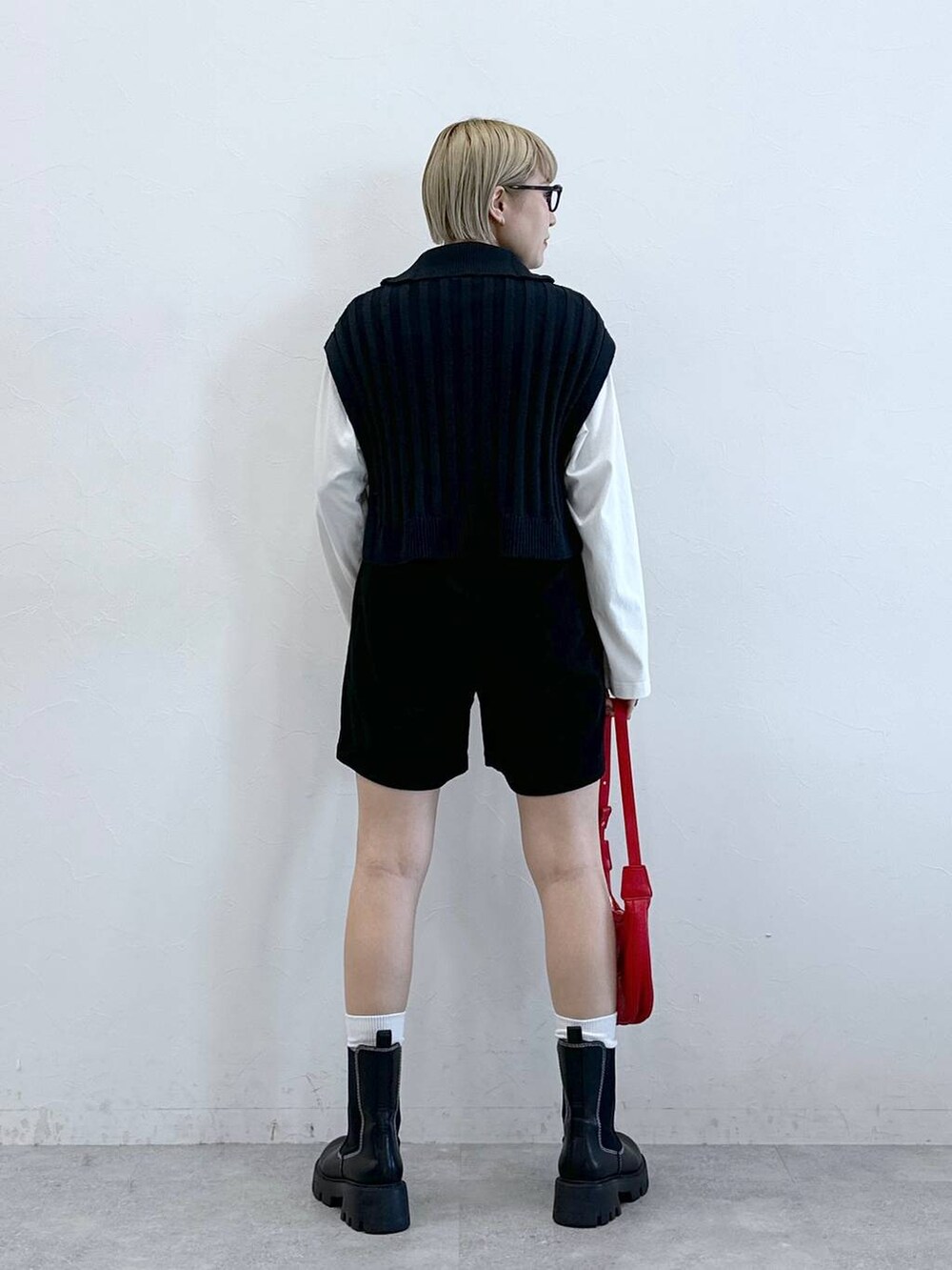 ブラック系のチノパンツ、レッド系のショルダーバッグ、ホワイト系のTシャツ/カットソーを着用したレディースの冬コーディネートの3枚目の写真