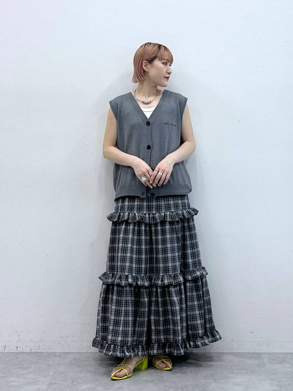 グレー系のベスト、ホワイト系のタンクトップ、ブラック系のスカートを着用したレディースの春コーディネートの3枚目の写真