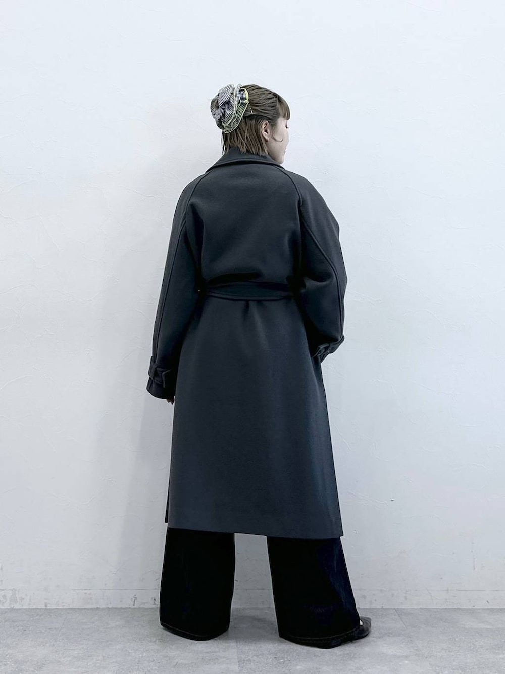 グレー系のステンカラーコート、ブラック系のニット/セーター、ブラック系のパンプスを着用したレディースの冬コーディネートの6枚目の写真