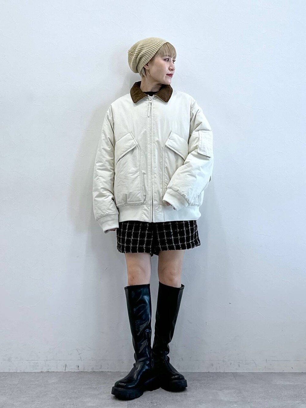 ブラック系のブーツ、ホワイト系のブルゾン、ブラウン系のその他パンツを着用したレディースの冬コーディネートの2枚目の写真