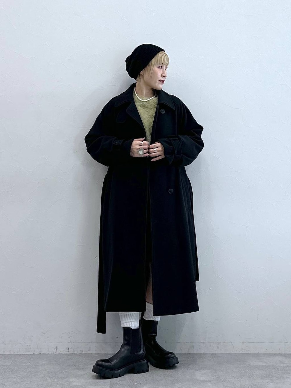 ブラック系のスラックス、イエロー系のニット/セーター、ブラック系のブーツを着用したレディースの秋コーディネートの2枚目の写真