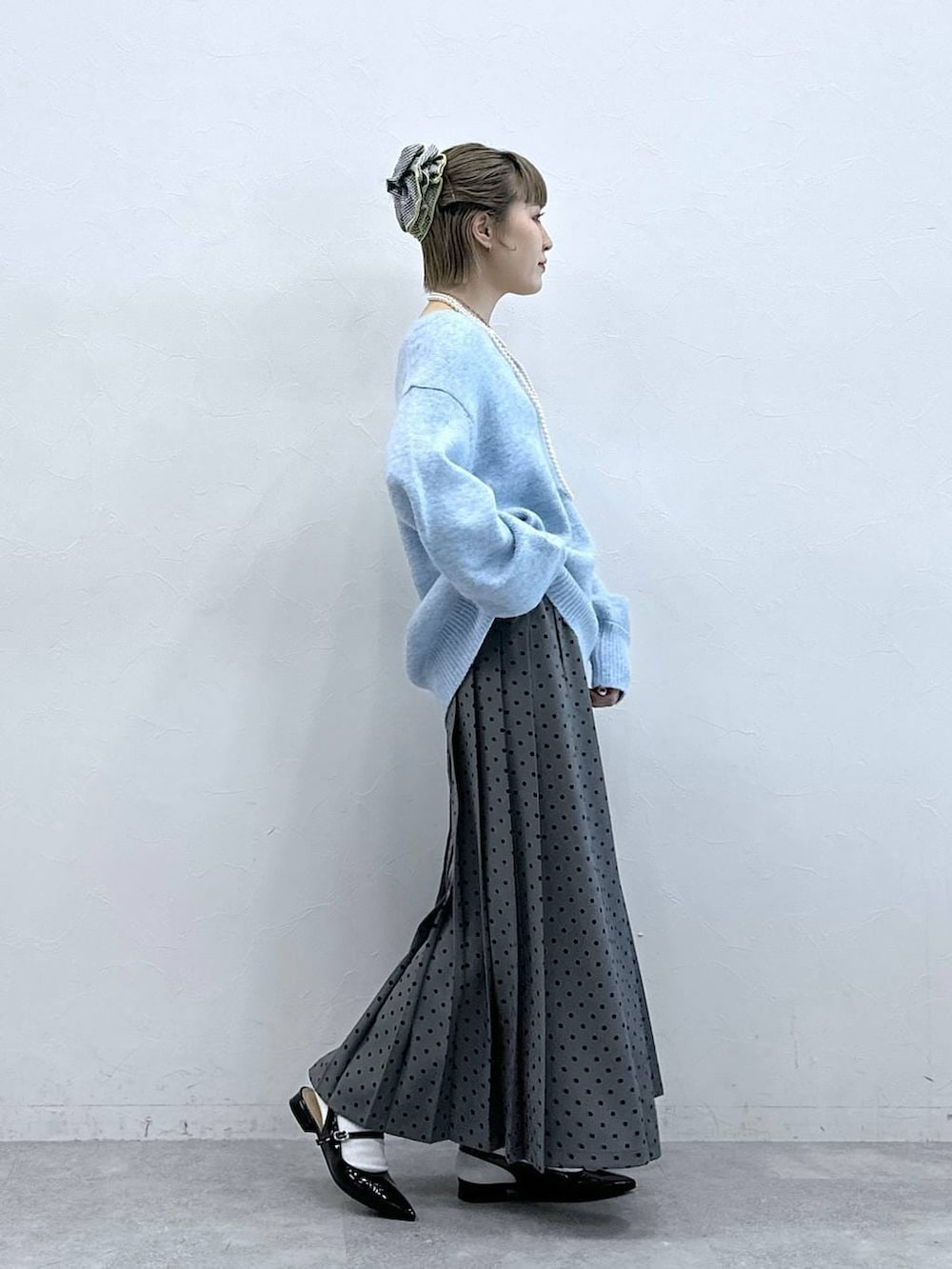 ブラック系のパンプス、ブルー系のニット/セーター、グレー系のスカートを着用したレディースの冬コーディネートの4枚目の写真