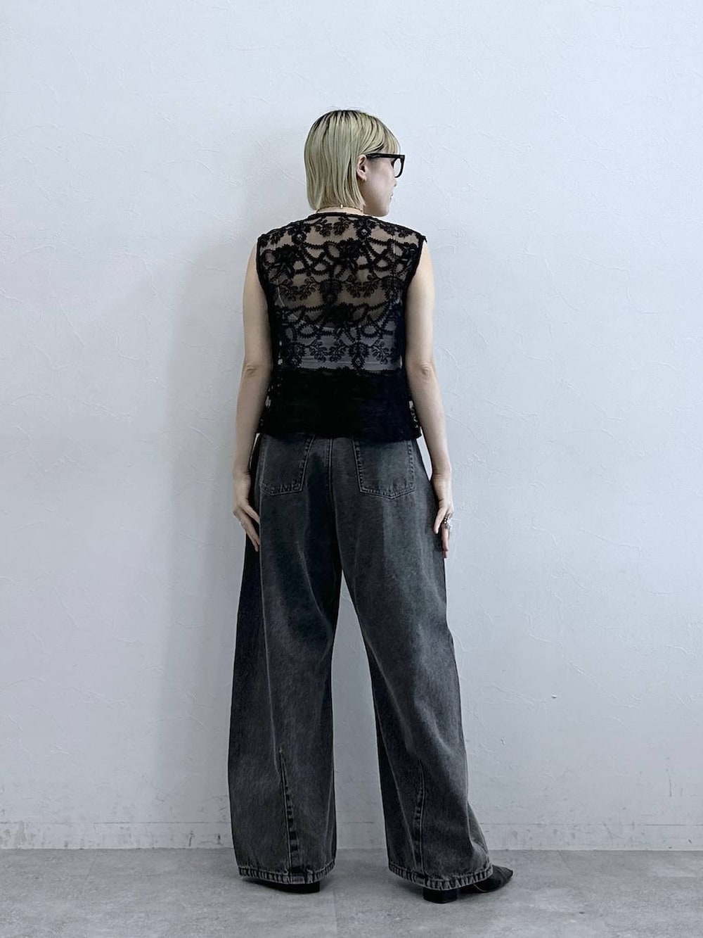 グレー系のデニムパンツ、ブラック系のベスト、ホワイト系のブラジャーを着用したレディースの夏コーディネートの6枚目の写真
