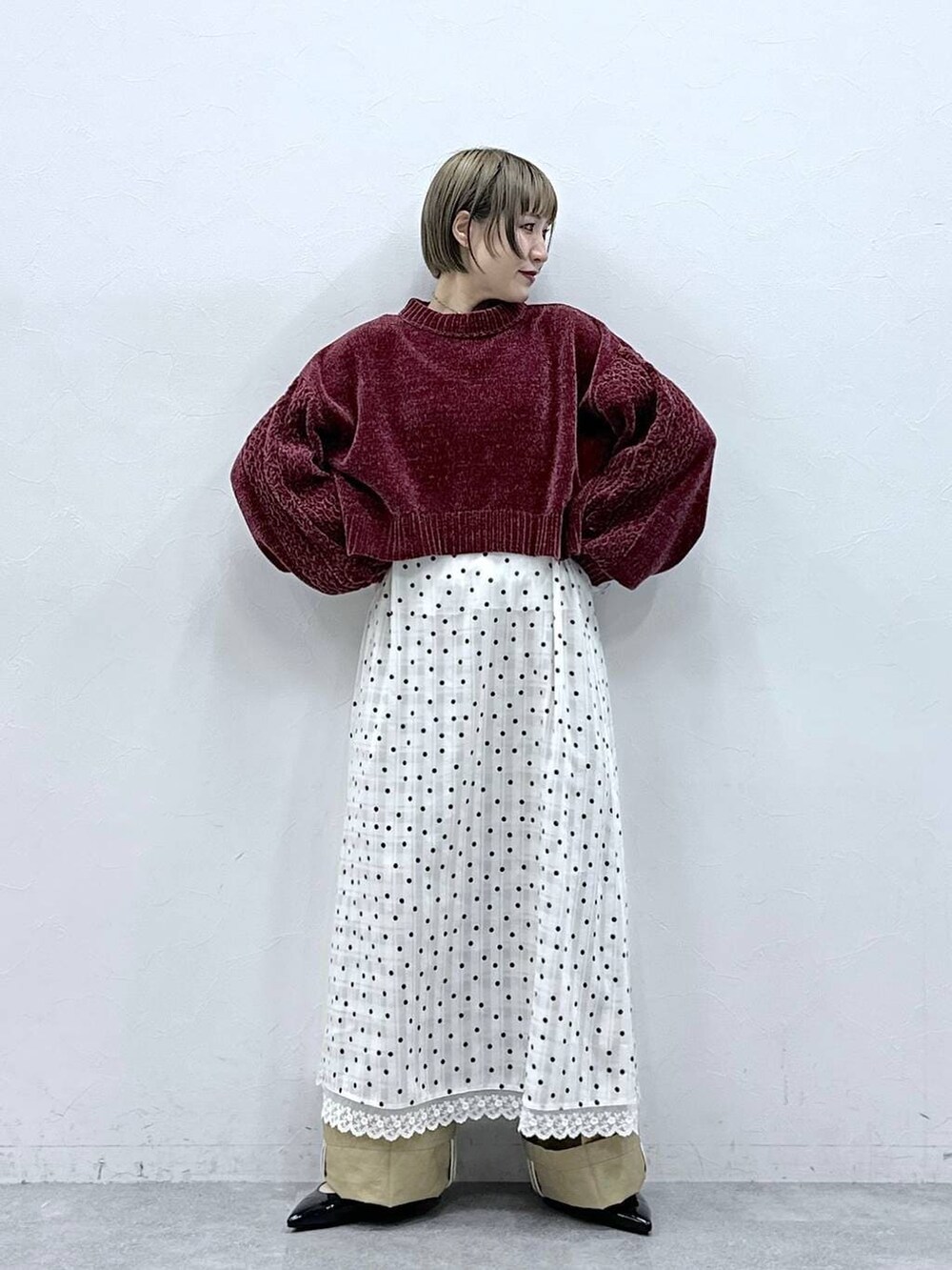 レッド系のニット/セーター、ブラック系のパンプス、ベージュ系のチノパンツを着用したレディースの冬コーディネートの3枚目の写真