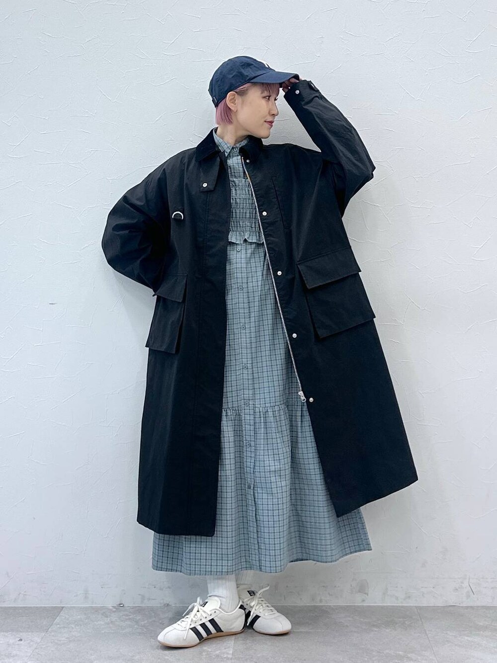 ブラック系のステンカラーコート、ホワイト系のスニーカー、ブルー系のシャツワンピースを着用したレディースの冬コーディネートの5枚目の写真