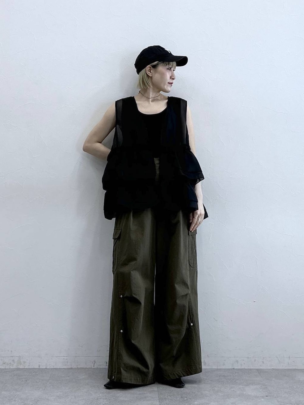 グリーン系のカーゴパンツ、ブラック系のタンクトップ、ブラック系のベストを着用したレディースの夏コーディネートの2枚目の写真