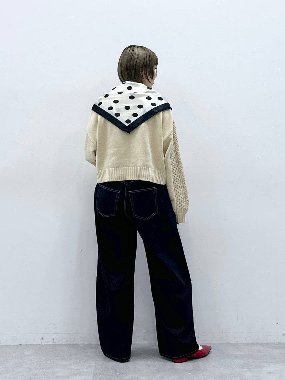 ホワイト系のニット/セーター、レッド系のパンプス、ブラック系のデニムパンツを着用したレディースの冬コーディネートの6枚目の写真