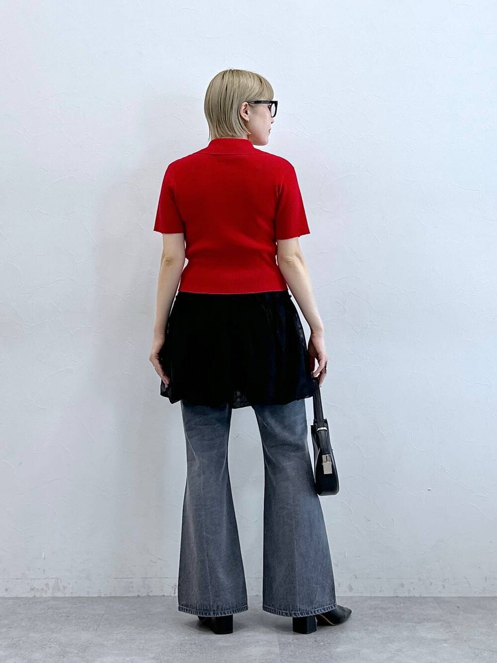 レッド系のニット/セーター、グレー系のデニムパンツ、ブラック系のスカートを着用したレディースの夏コーディネートの7枚目の写真
