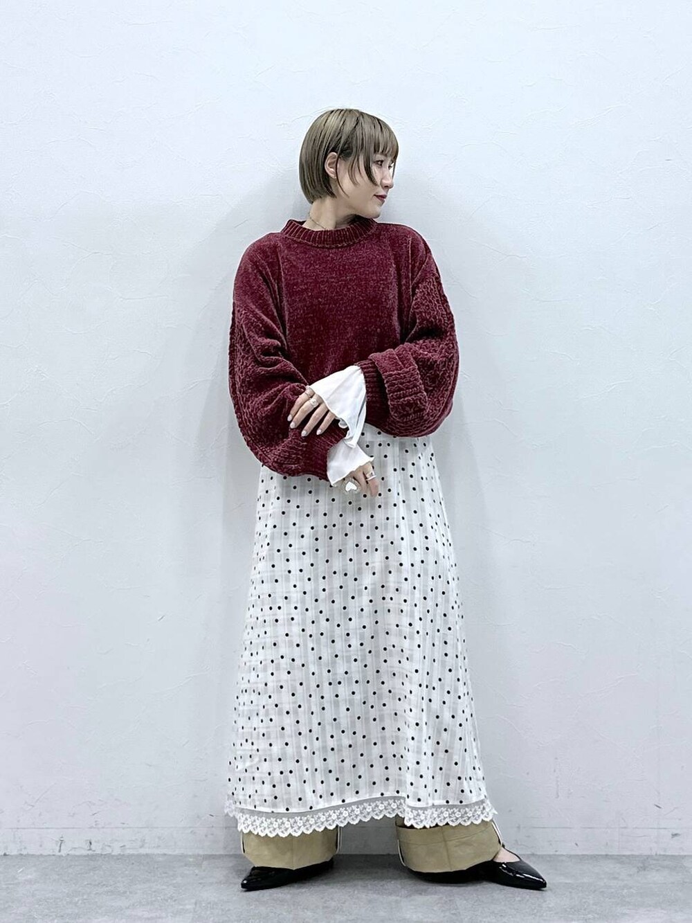 レッド系のニット/セーター、ブラック系のパンプス、ベージュ系のチノパンツを着用したレディースの冬コーディネートの5枚目の写真