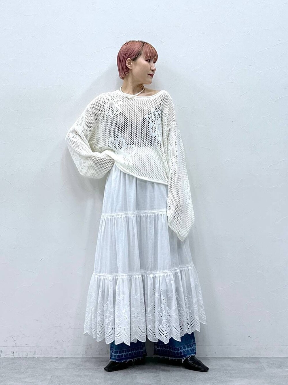 ブルー系のデニムパンツ、ホワイト系のニット/セーター、ホワイト系のスカートを着用したレディースの春コーディネートの4枚目の写真