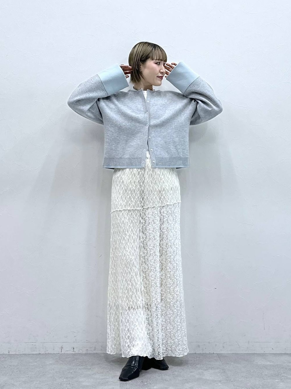 グレー系のカーディガン/ボレロ、ホワイト系のスカートを着用したレディースの冬コーディネートの3枚目の写真